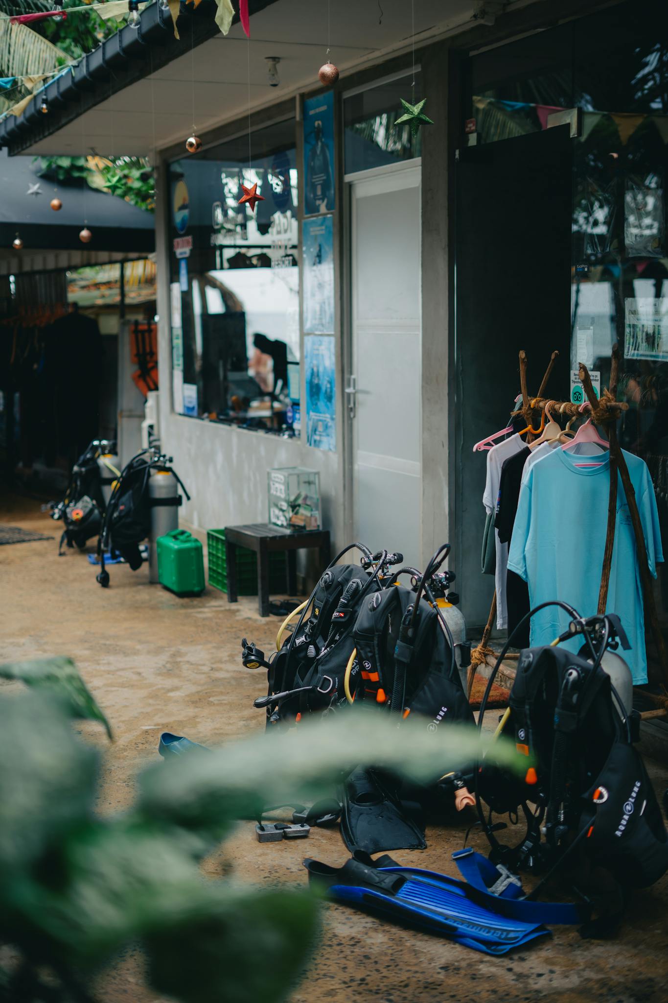 Outdoor display of scuba diving gear including wetsuits and tanks at a dive center.